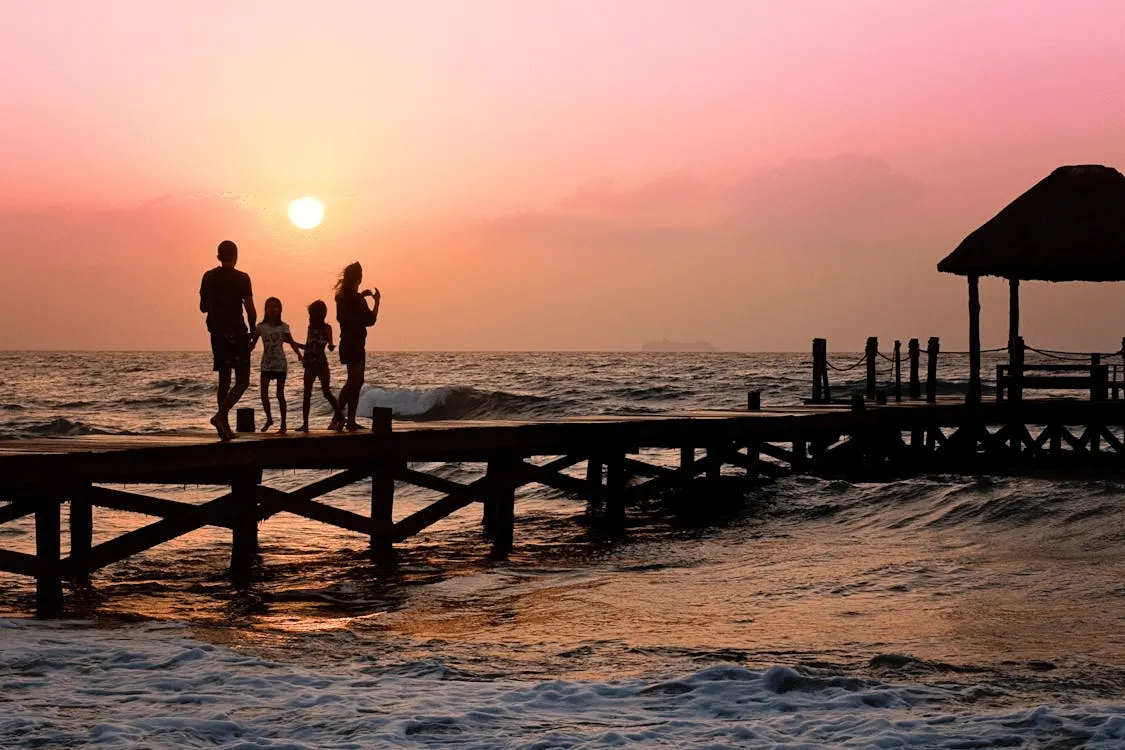 Family standing on a dock during sunset, prepared for safe travel abroad.