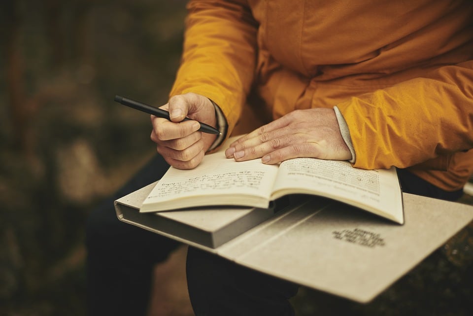 woman writing down journaling bucket list dreams