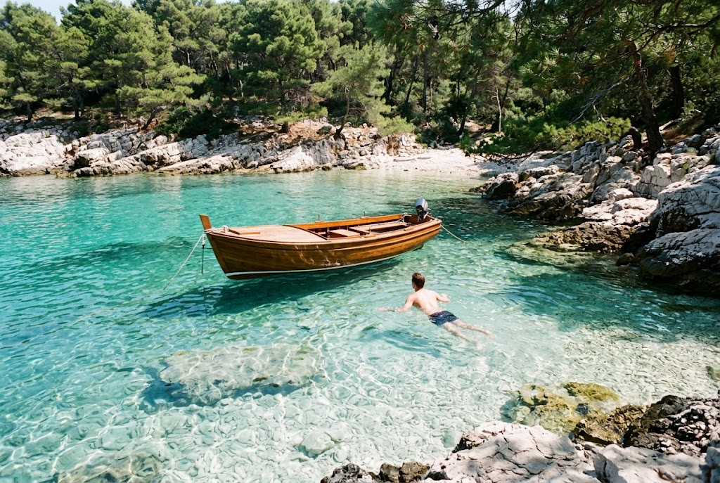 A small boat anchored in a clear turquoise cove in the Pakleni Islands off Hvar, Croatia, one of the best travel destinations for $2500 to $5000